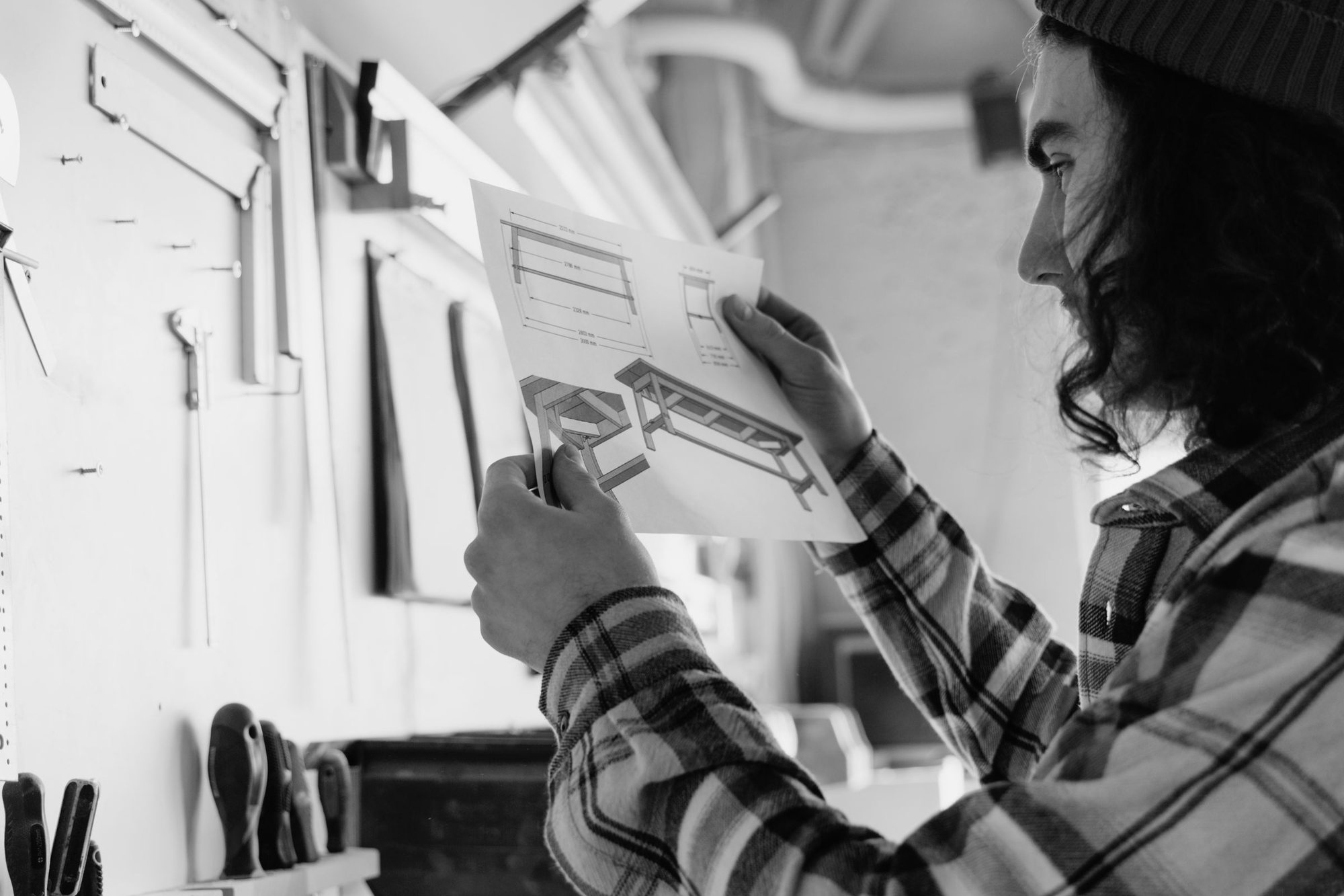 A carpenter in a workshop reading a furniture design